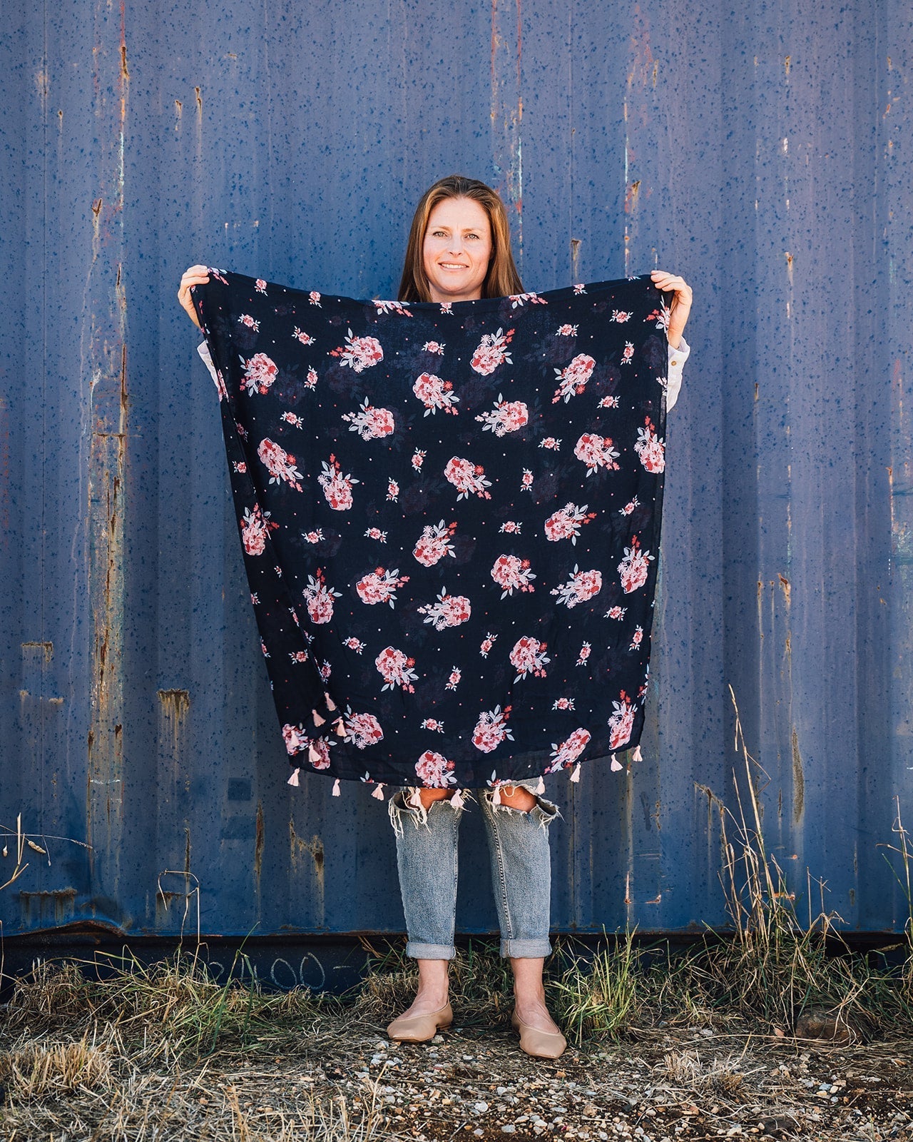 Cassie Cottage Women's Scarf: English garden-inspired floral print in light and raspberry pinks, with a touch of light blue on a navy base. Adorned with light pink tassels. Elevate your style with Cassie's blooming charm!
