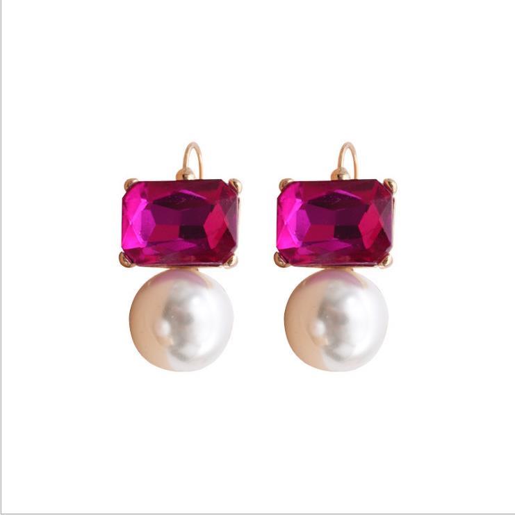 A pair of earrings featuring bright pink rectangular crystals above faux pearls, with gold plated earring hooks and settings.
